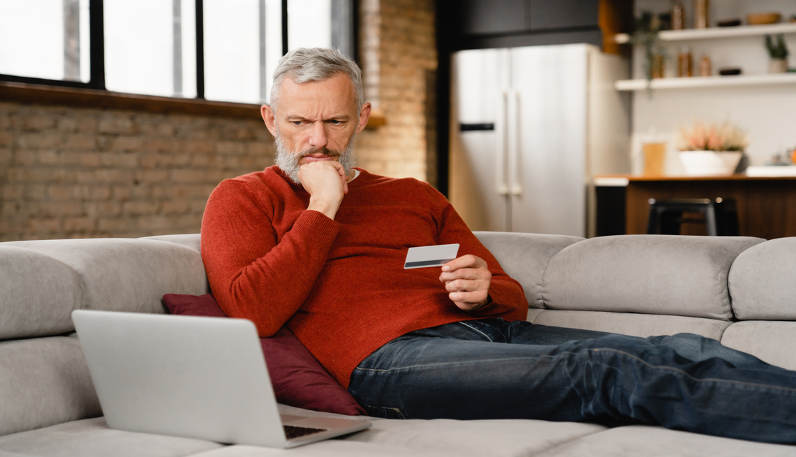 Mature middle-aged man doing shopping online, buying purchasing presents clothes remotely, ordering food delivery with credit card e-commerce banking on laptop at home